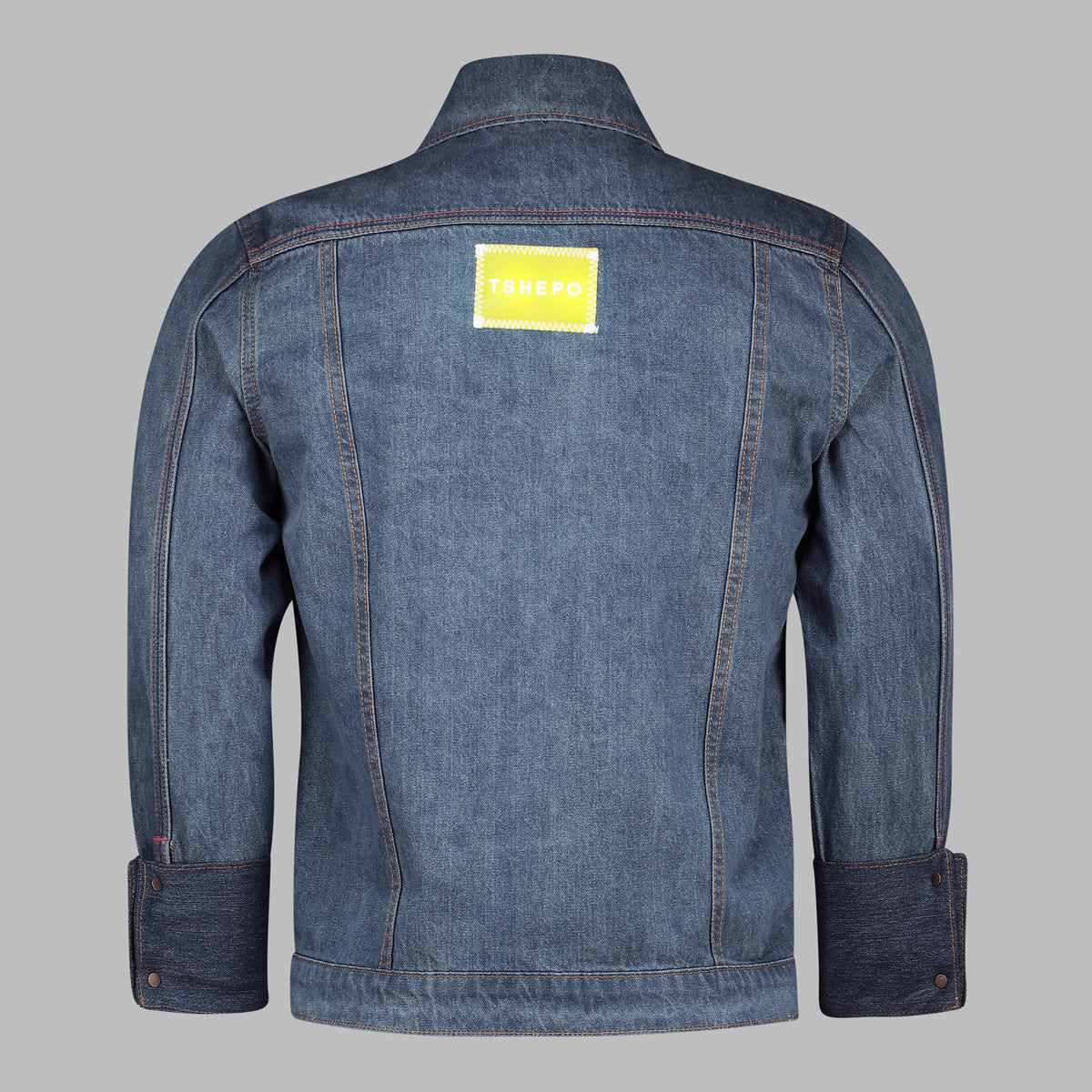 The full back of a TSHEPO Light wash trucker jacket with a yellow leather patch