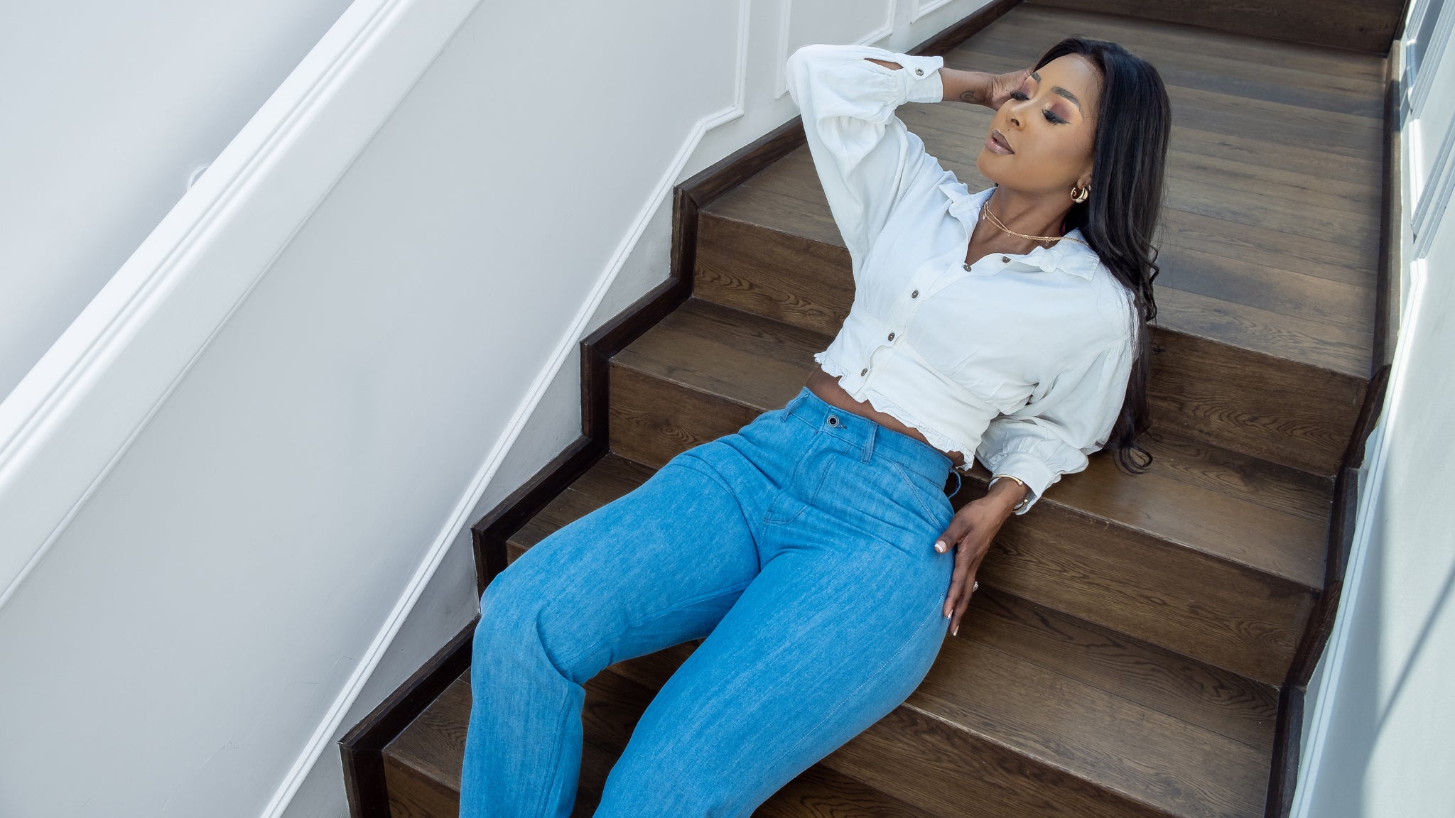 Tshepo model sitting on stairs wearing a white crop top wearing a light wash TSHEPO Pakisha jean